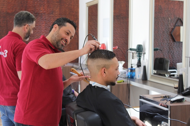 Hafid Belghazi dans son salon de coiffure vec un client