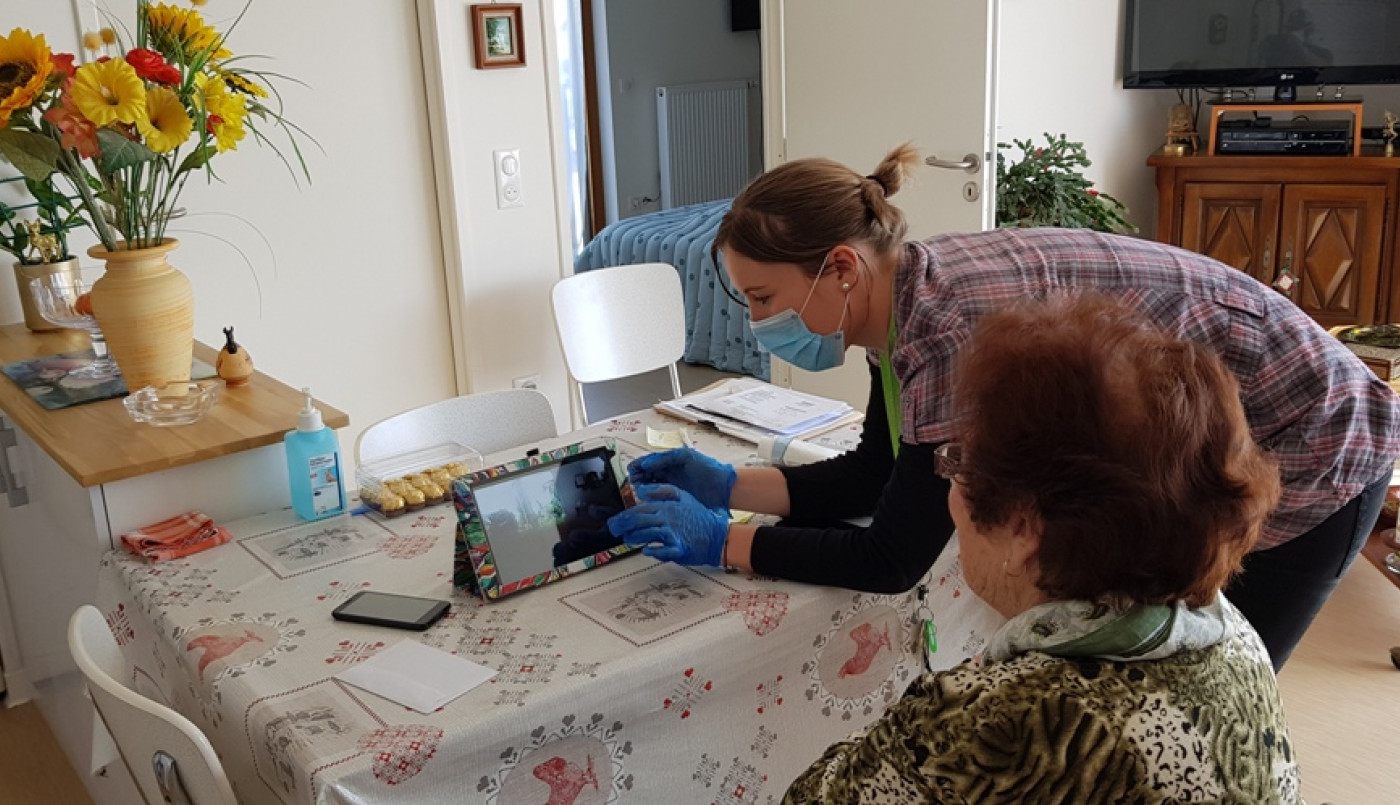 Une animatrice accompagne une résidente pour un visio rendez-vous avec sa famille